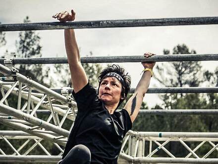 Athlète suspendue à une barre sur une course à obstacles