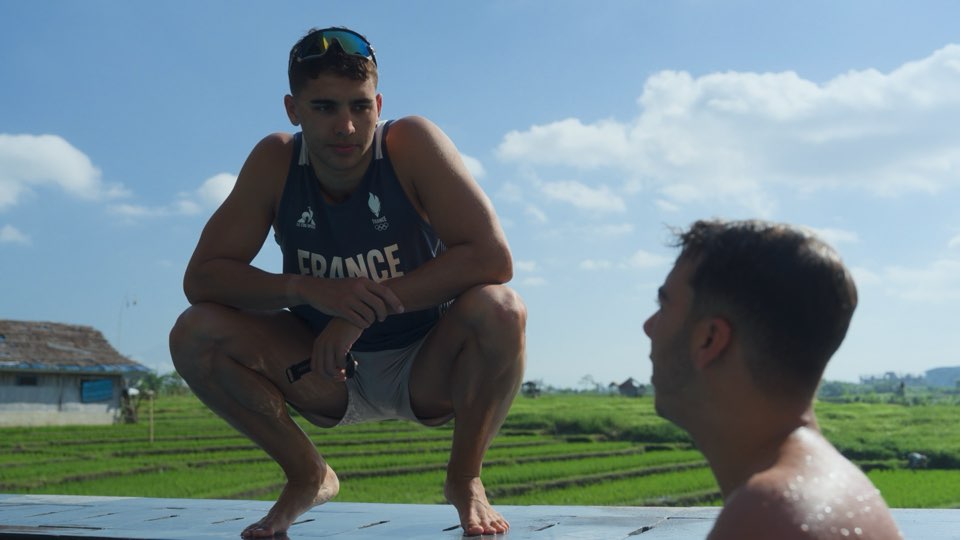 Amazigh Yebba en maillot de l'équipe de France, accroupi près d'un nageur dans l'eau